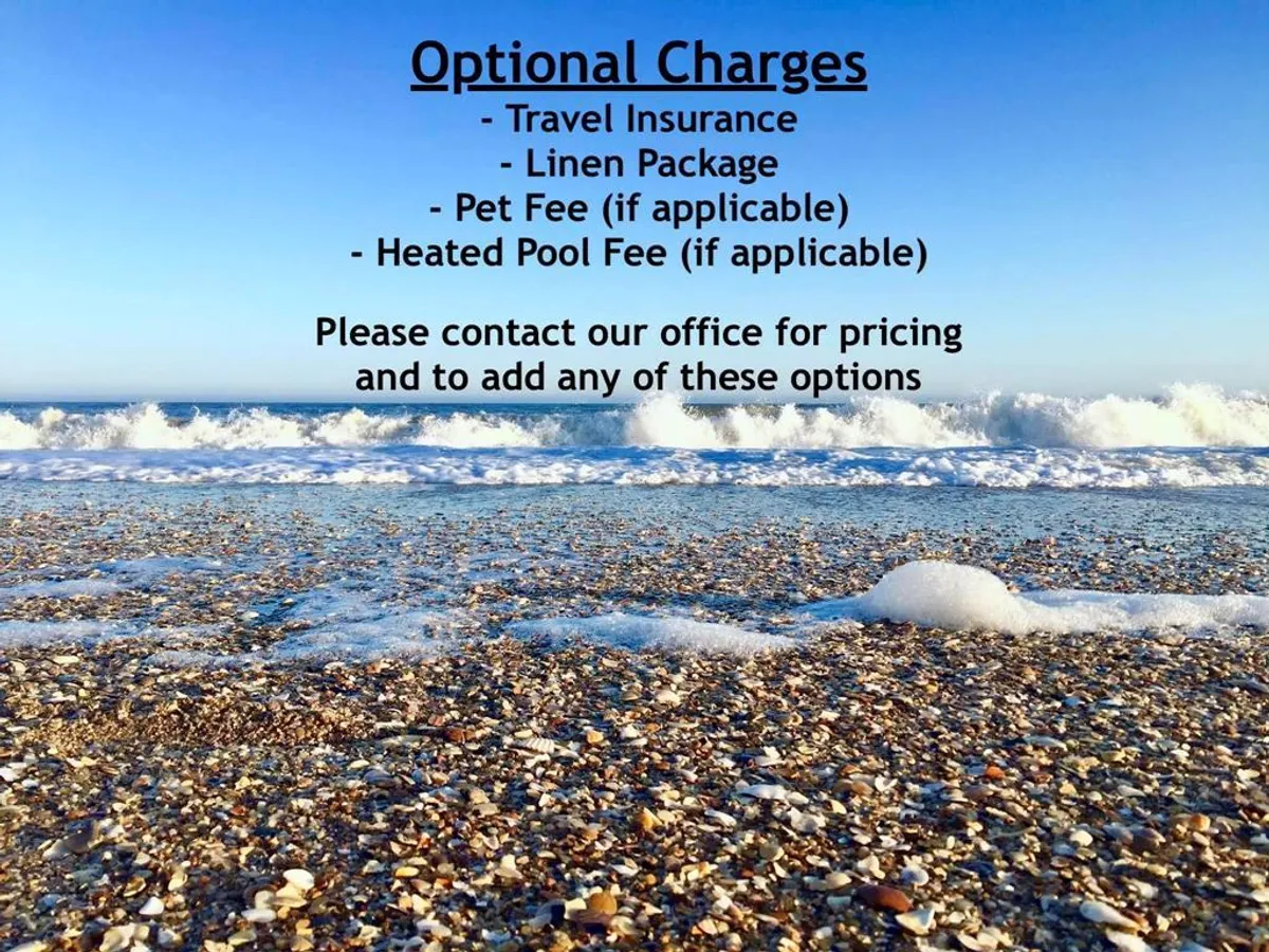A serene scene of ocean waves gently lapping the sandy beach, with seashells scattered along the shore and a clear blue sky overhead. The view evokes the effortless access to beachfront walks and the laid-back coastal lifestyle available just across the street.