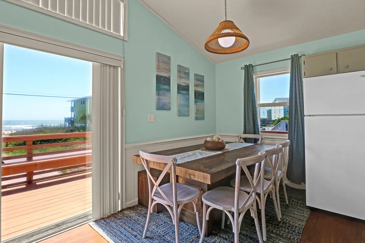 A stylish dining area featuring a table set for a meal, artwork on the wall, and a large window with a scenic view. The mood is warm and welcoming, suggesting both lively family meals and quiet moments. While the kitchen itself is not pictured, the adjacency to the dining area and visible connection to shared spaces supports the narrative of togetherness.