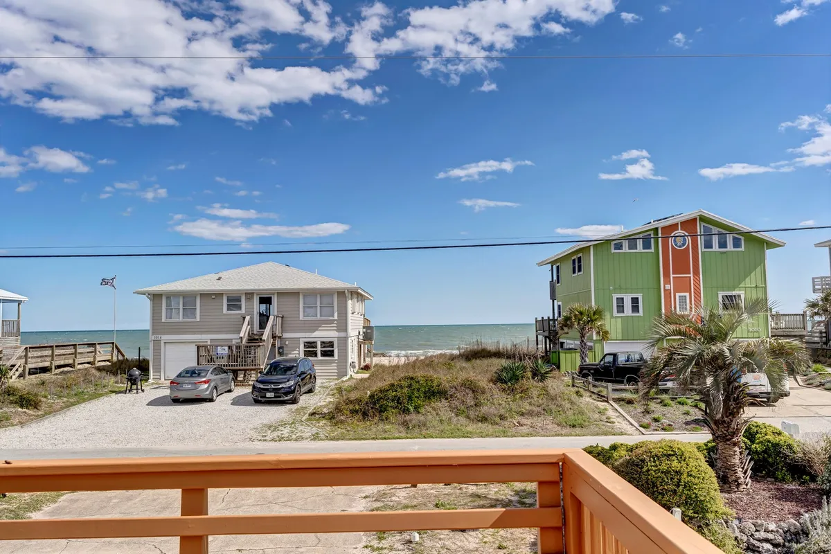 This image shows a vibrant ocean view framed by colorful houses and palm trees, with a parking area below. It captures the laid-back, coastal vibe and proximity to the beach, suggesting easy access for daytime adventures and evening strolls into town.